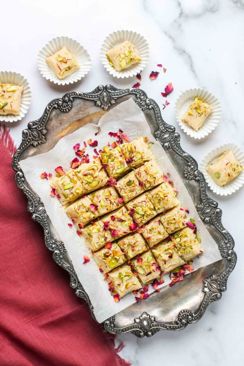 kalakand cubes in a silver platter and paper cupcake liners