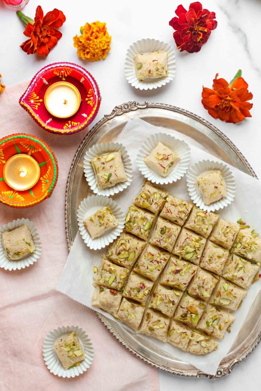 kalakand cubes in a silver platter and paper cupcake liners