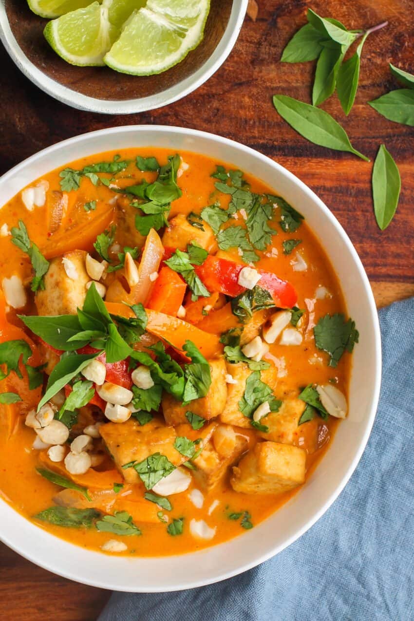 Thai Panang Curry garnished with basil and peanuts served in a white bowl 