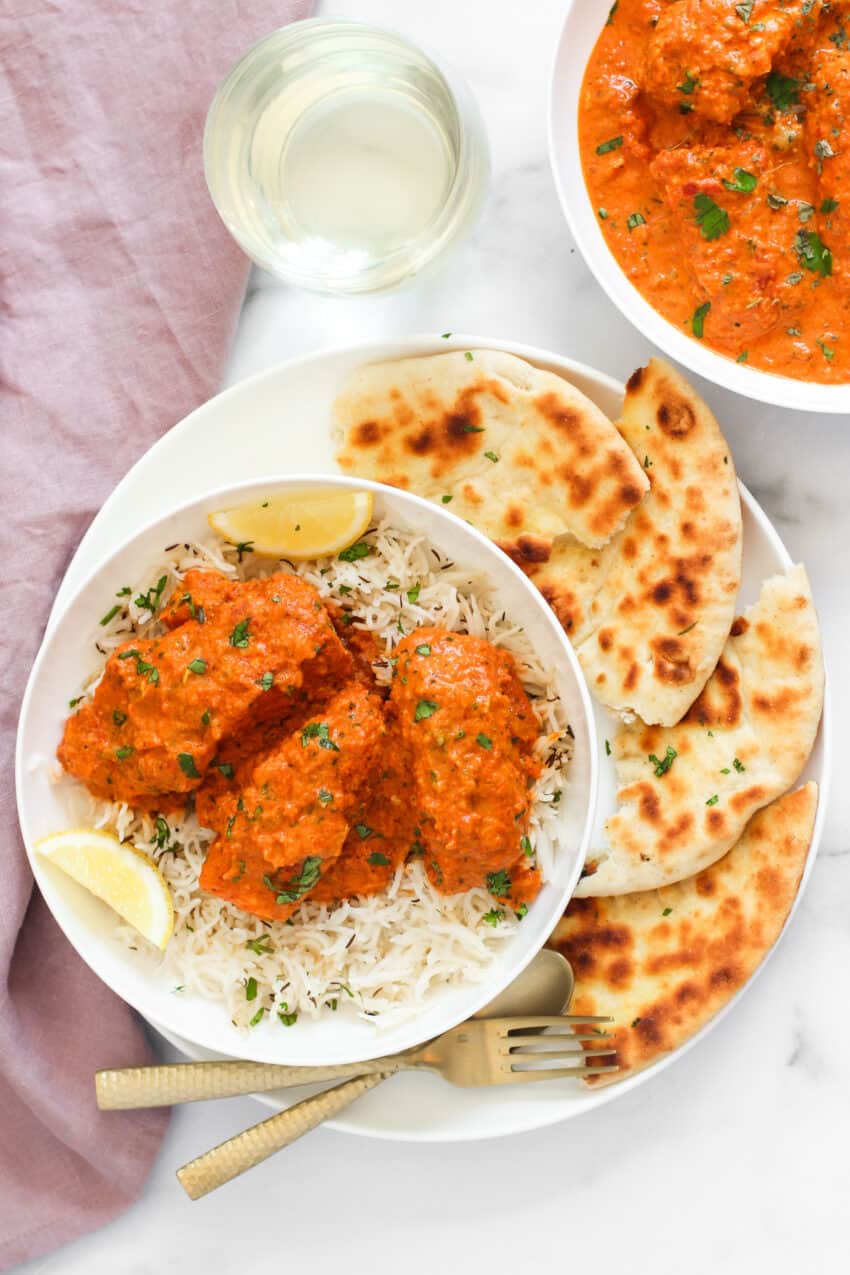 A plate of Salmon Tikka Masala, Indian flatbread, and rice.