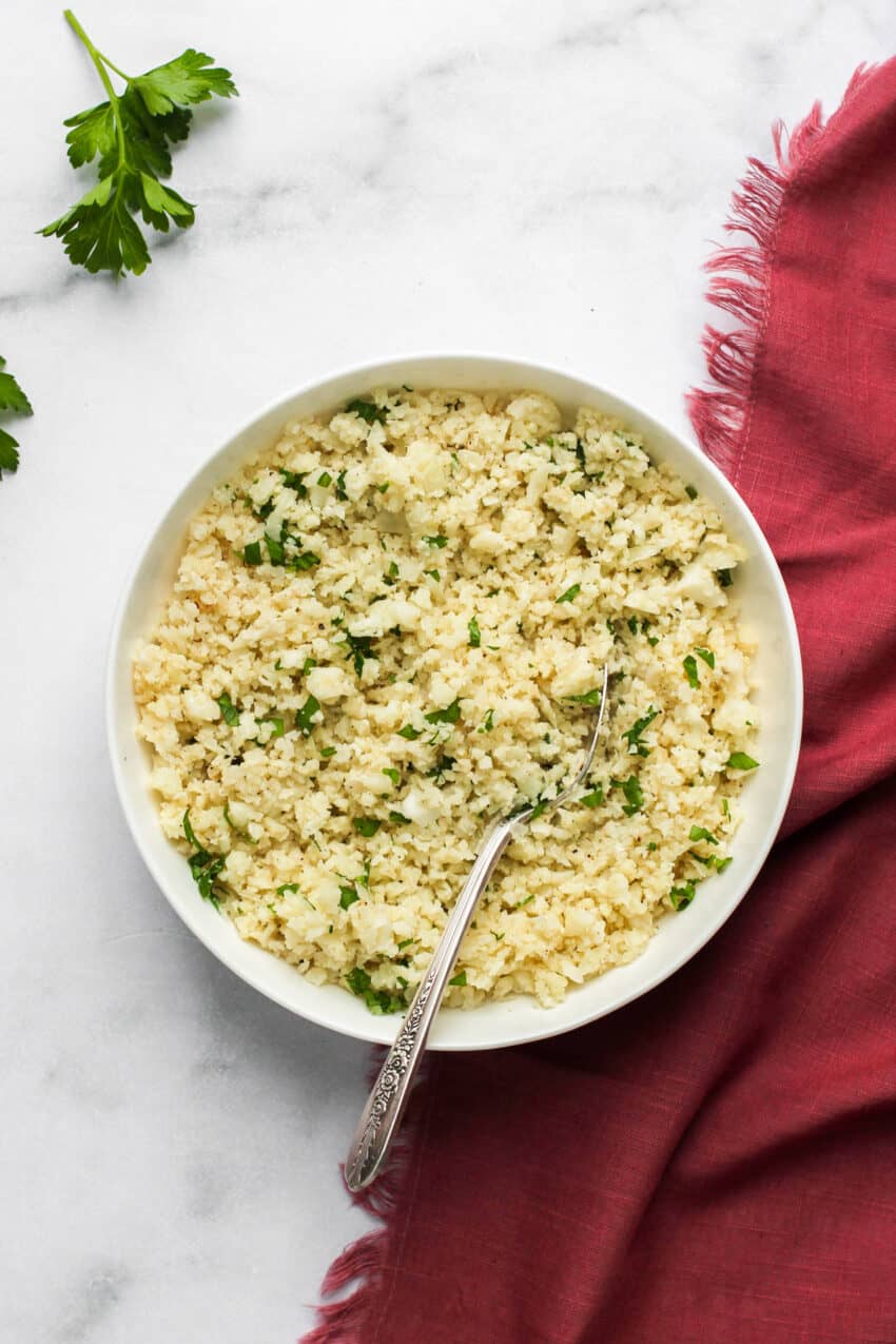 cauliflower rice in a white bowl with a spoon