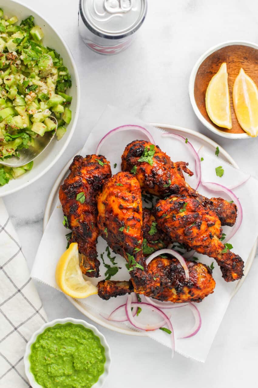 tandoori chicken with lemon wedges and cucumber salad