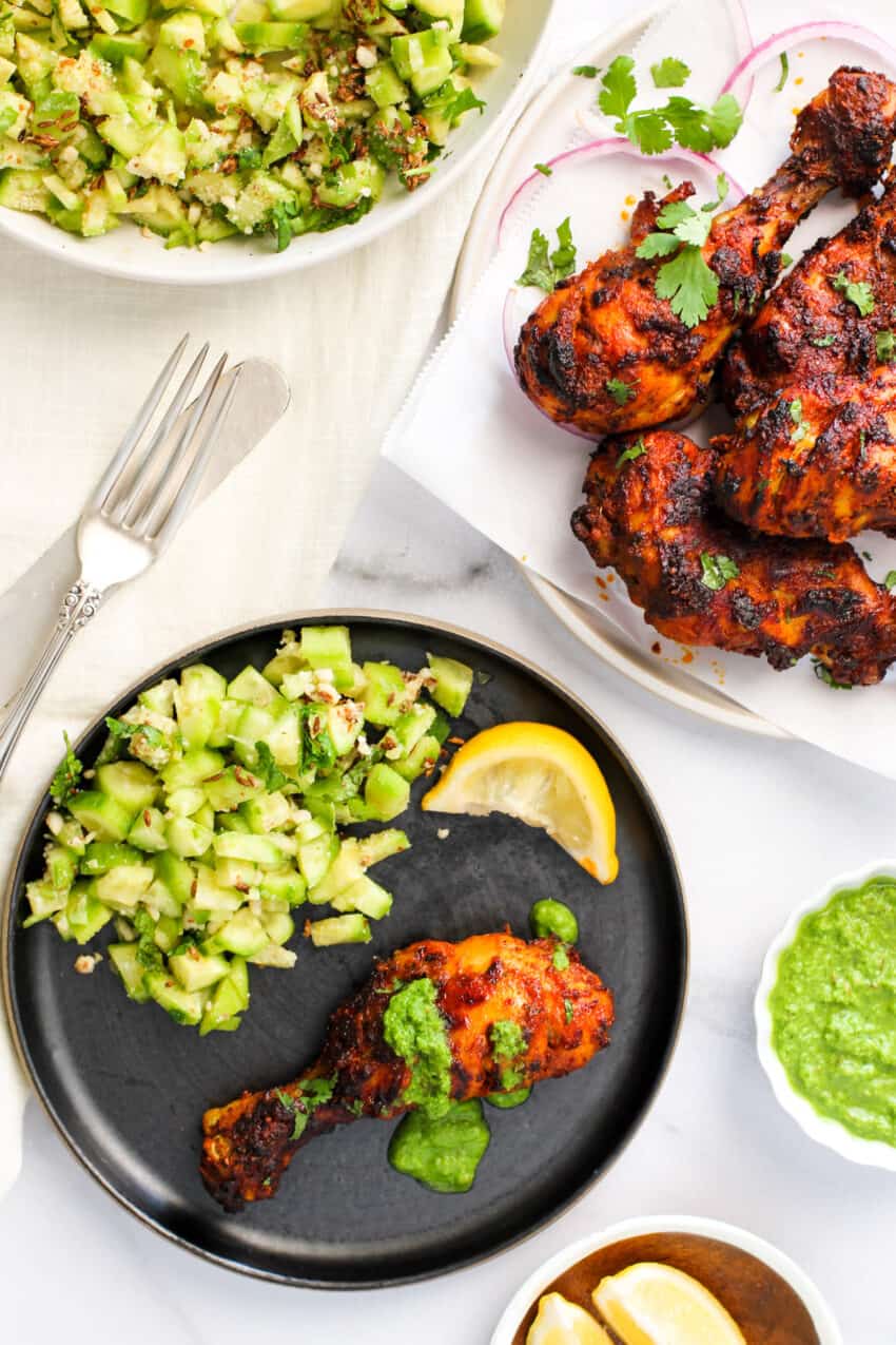tandoori chicken with lemon wedges and cucumber salad