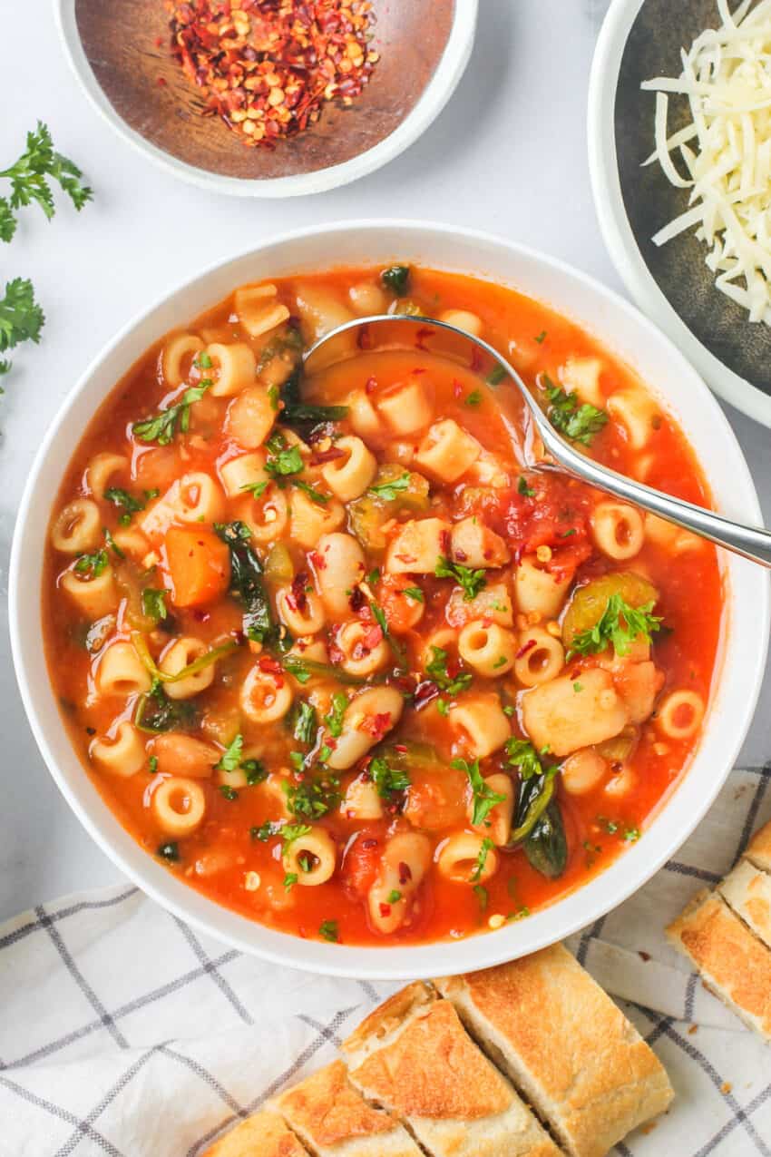 white bowl with soup in it and baguette on side