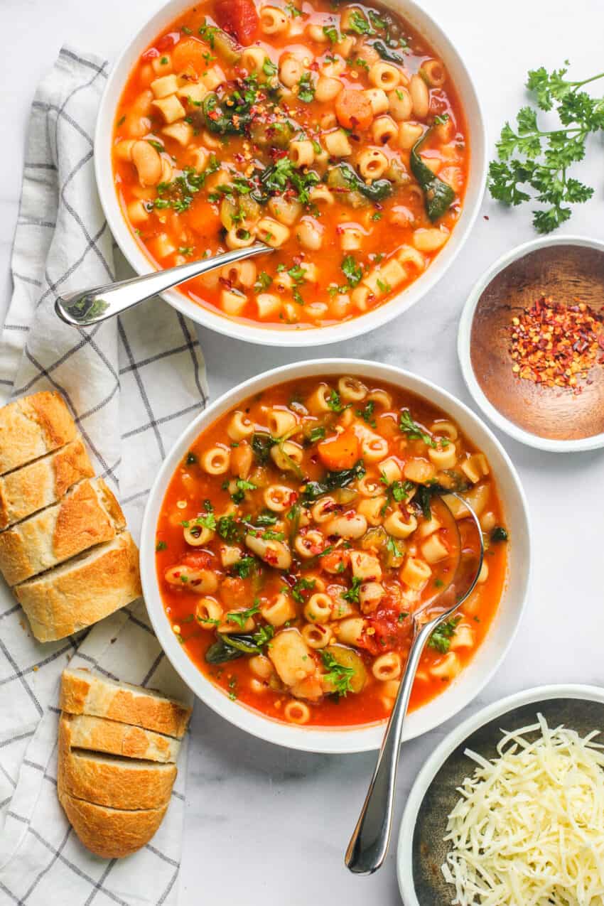 two white bowls with pasta fagioli soup in them