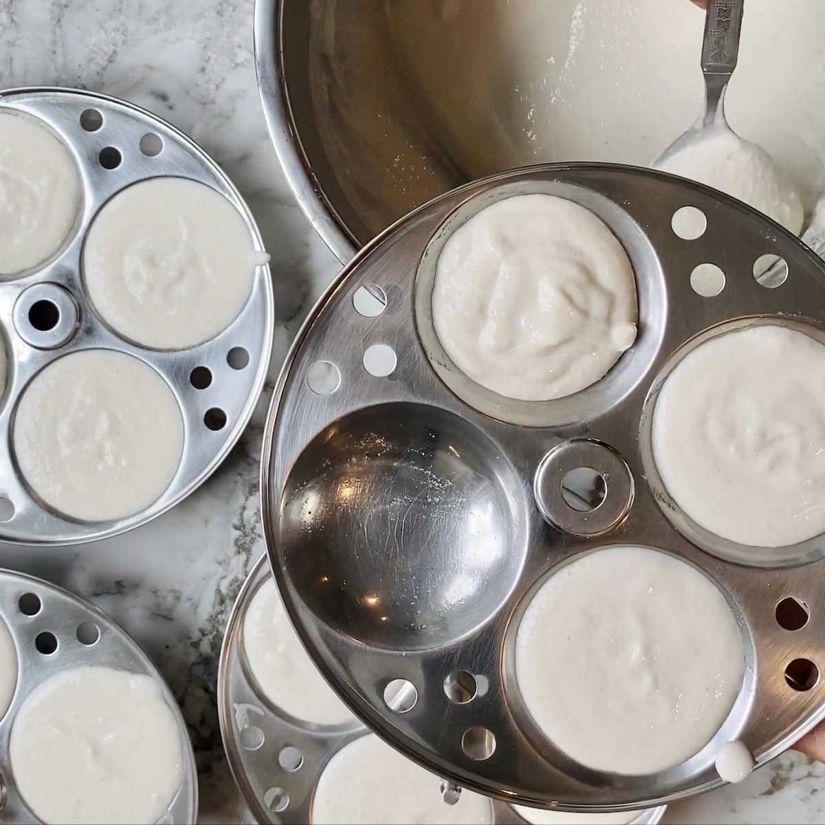 adding idli batter to the moulds