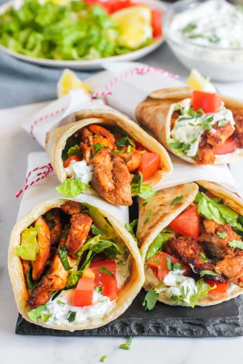 Assembled chicken shawarma rolls served on a black platter