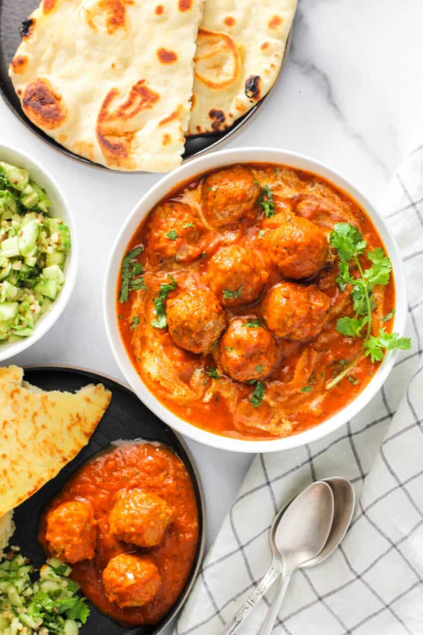 malai kofta servedin a white bowl with naan next to it.
