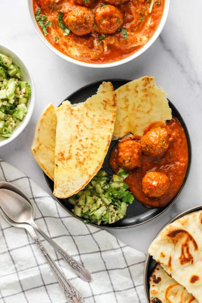 kofta curry served with naan and cucumber salad.
