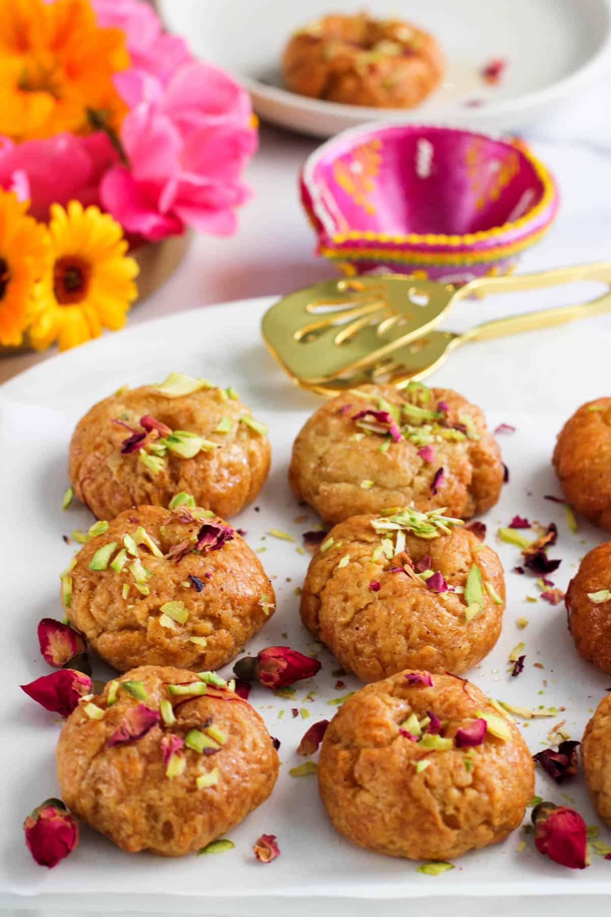 Balushahi garnished with pistachios and rose petals