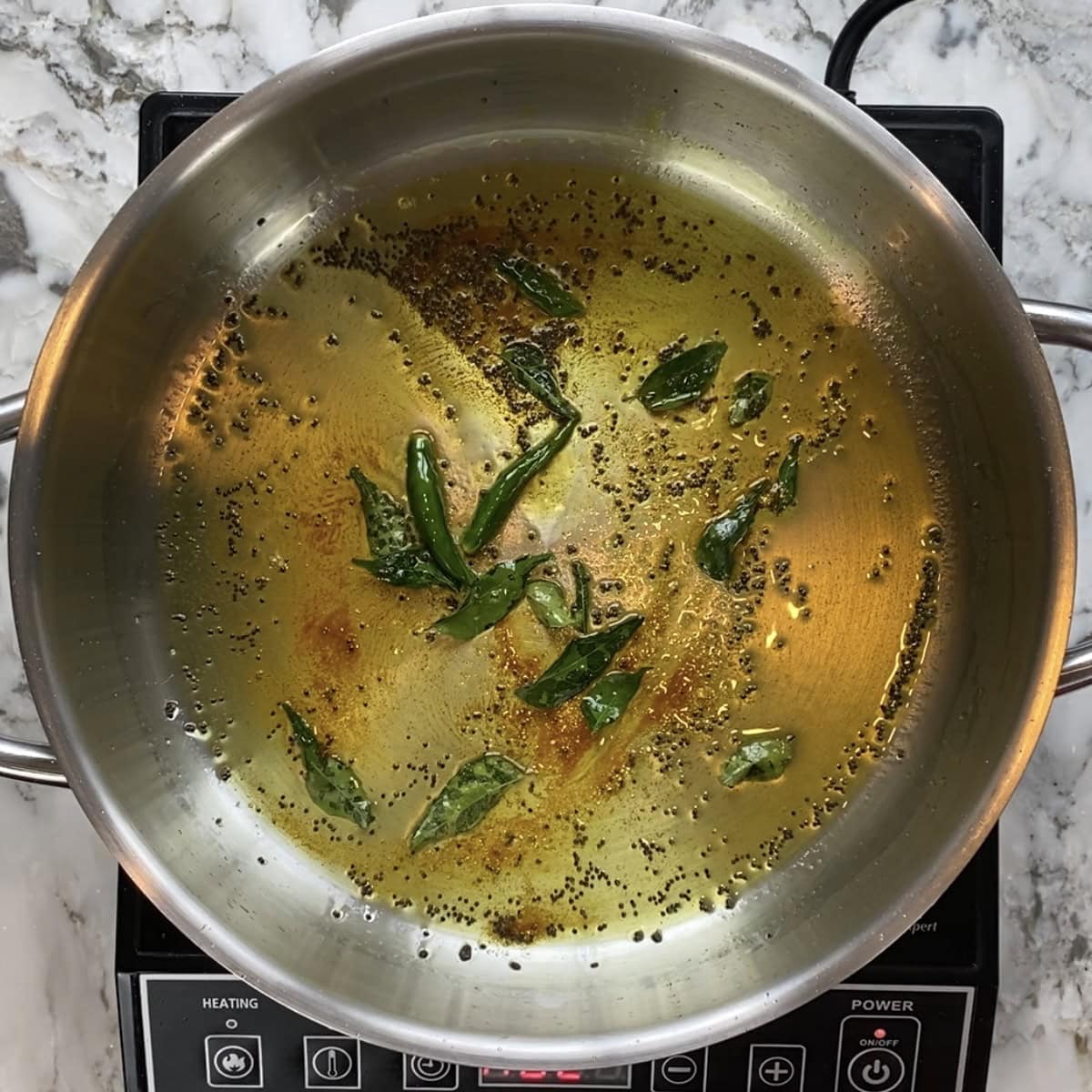 mustard seeds, curry leaves and turmeric tadka in a pan.