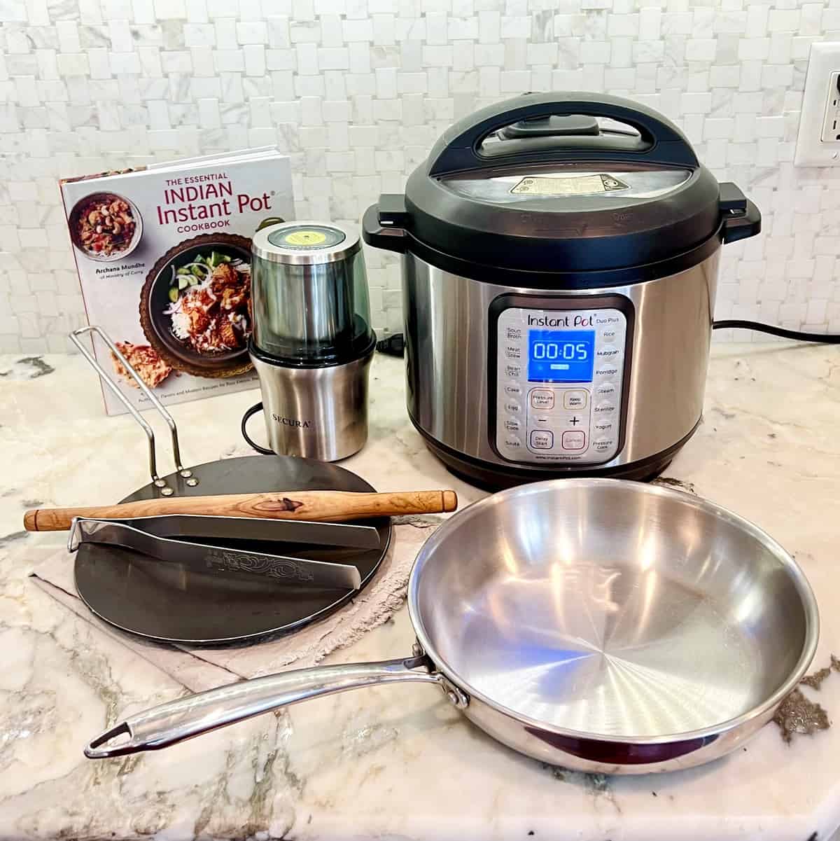 Indian cooking essentials - Instant Pot, Cookbook, spice grinder and pans on kitchen counter top