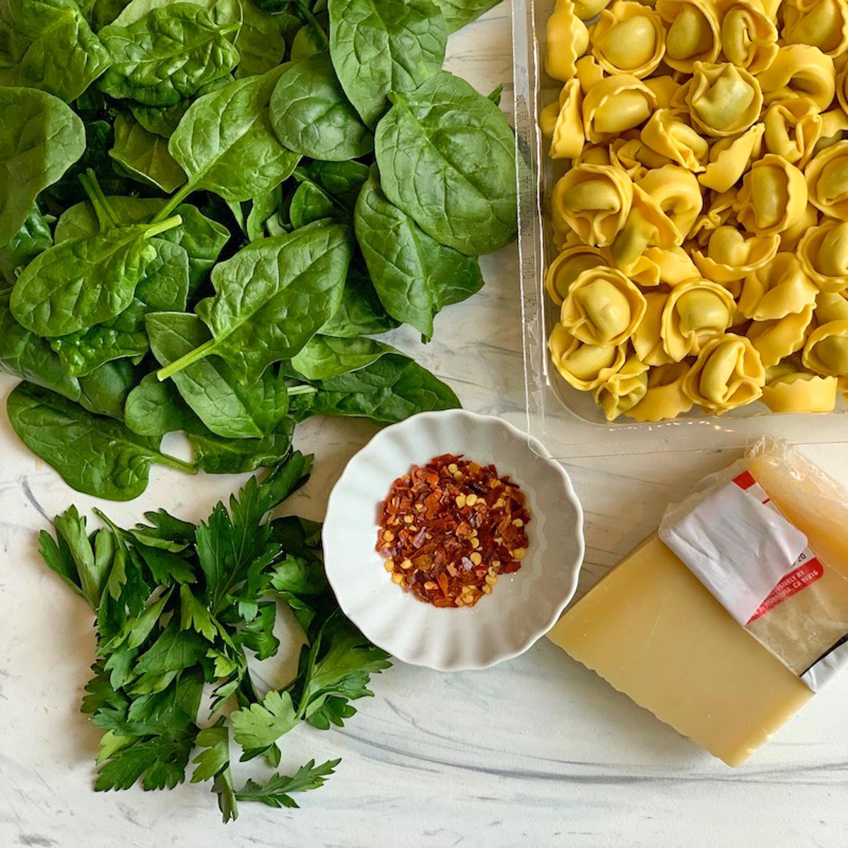 cheese, tortellini, spinach and parsley cutting board