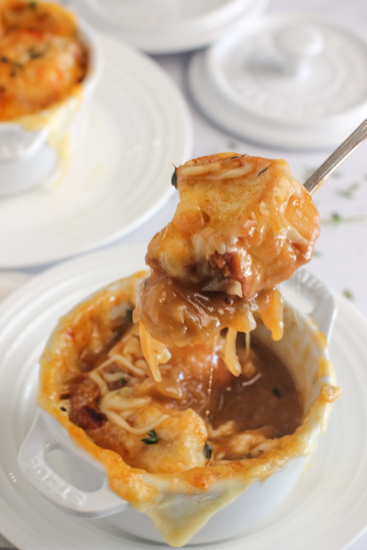 close up photo of a bowl and spoon with french onion soup 