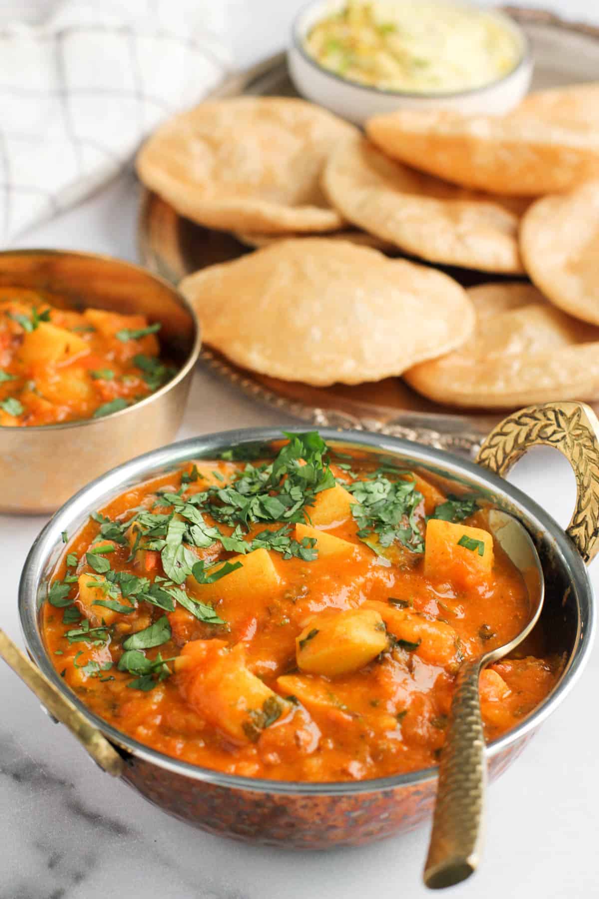 Aloo rasedar served in a small kadhai with Puri