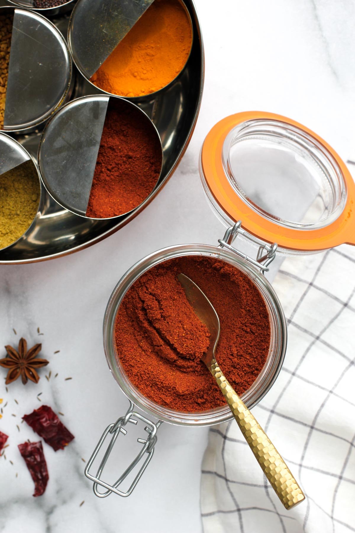 Garam Masala in a glass jar next to a spice box