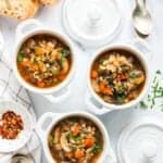 mushroom barley soup served in white bowls with sliced baguette on the side