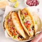 2 chalupas served in a white bowl topped with lettuce, tomatoes and cheese
