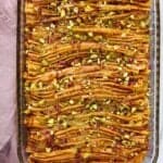 Phyllo dough crinkle cake garnished with pistachios and rose petals in a glass pan