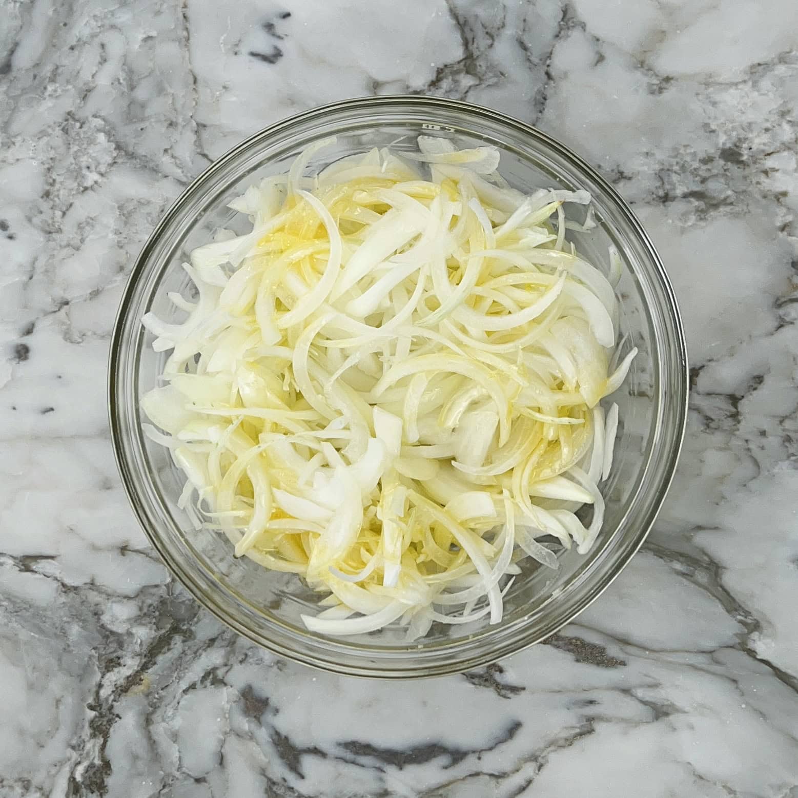 thinly sliced onions with ghee in a bowl.