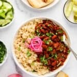 Rajma curry served with brown rice along side naan, lime wedges, cucumber and pickled onions