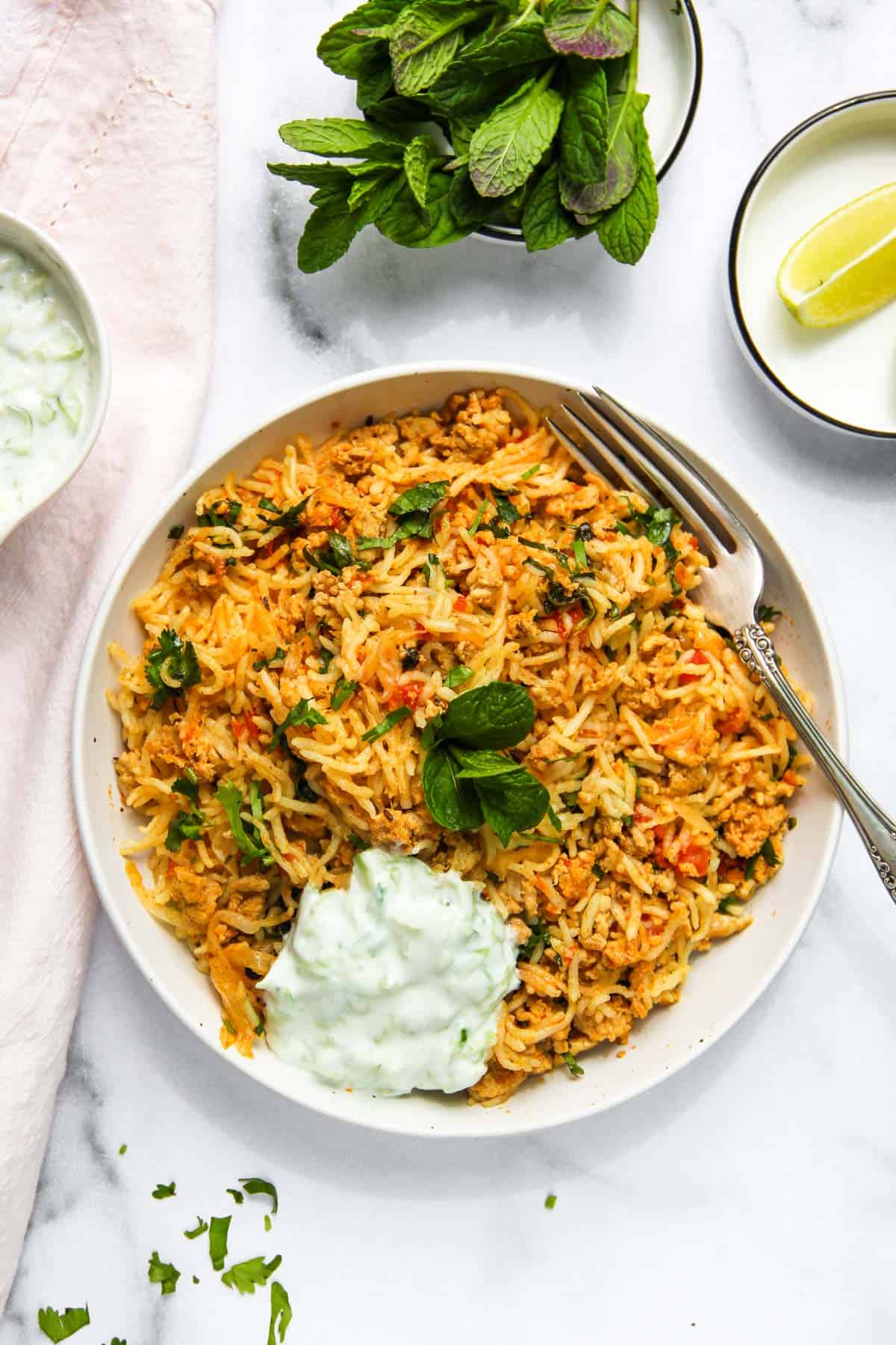 keema pulao served in white bowls with cucumber raita 