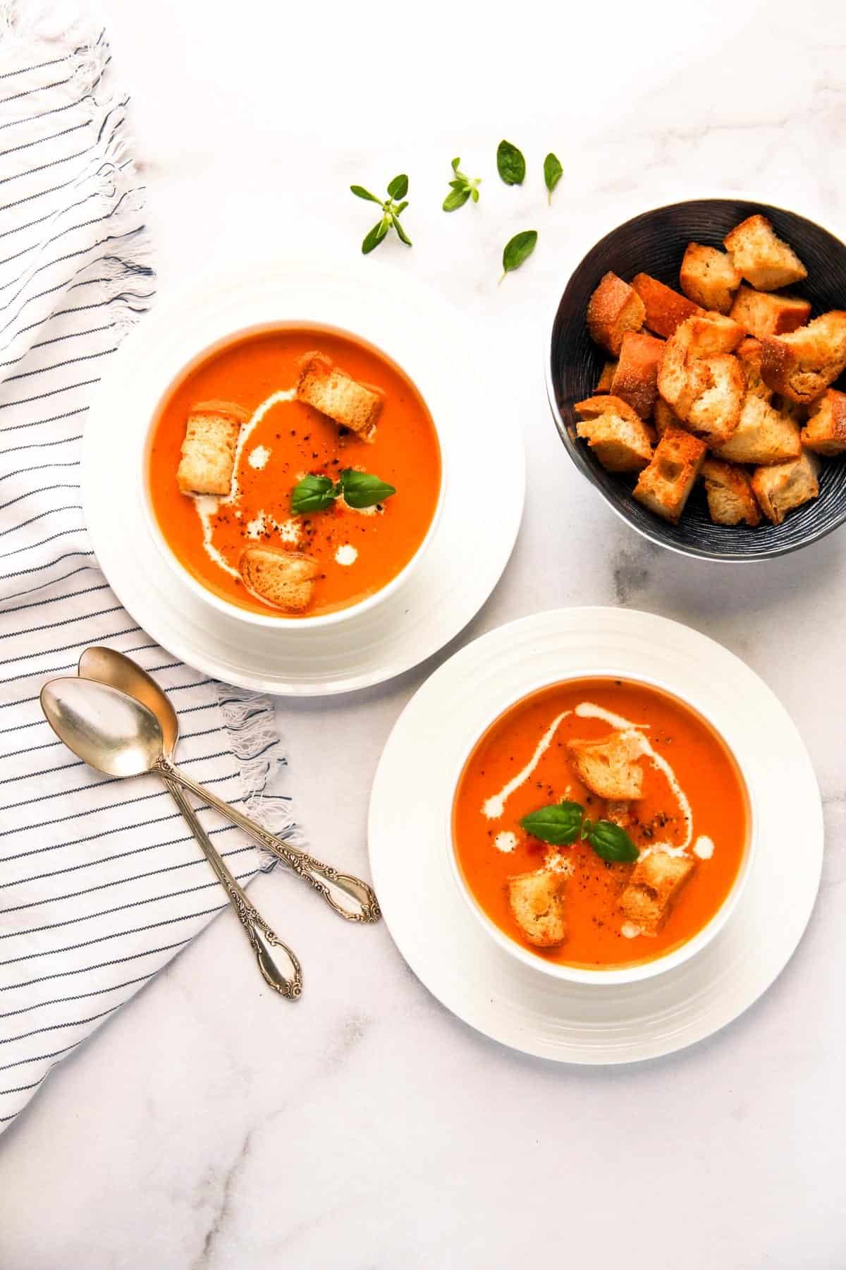Tomato bisque served in two white bowls with croutons 