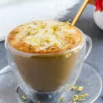 Pistachio latte served in a glass cup and saucer