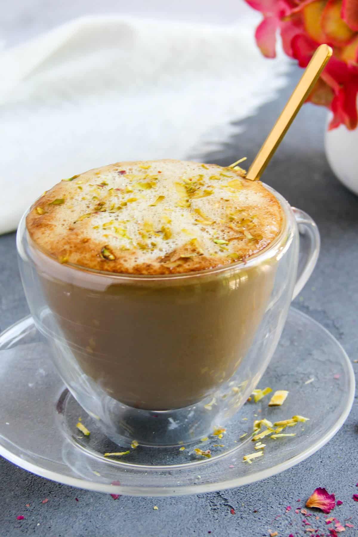 pistachio latte served in a glass cup and saucer 