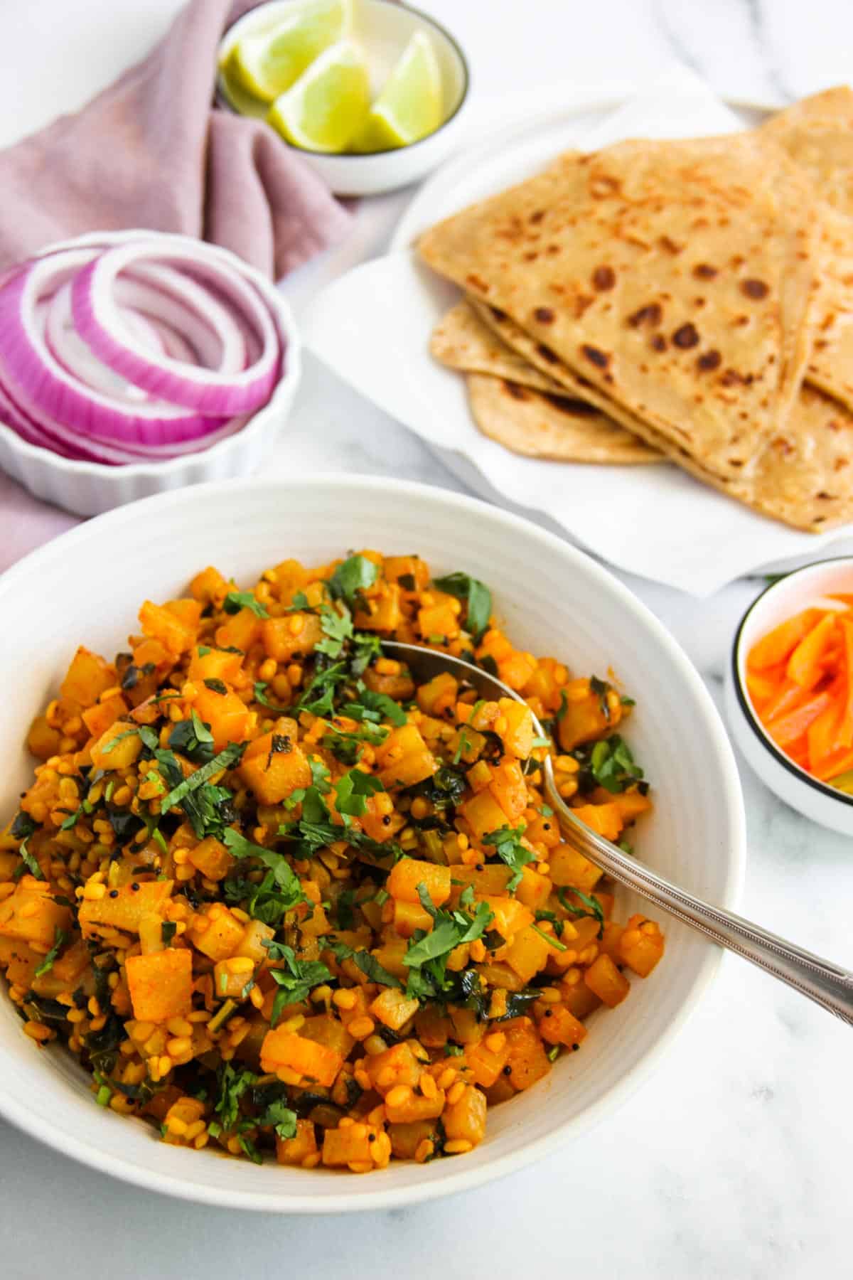 Kohlrabi curry served in a white bowl with parathas 