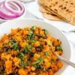 Kohlrabi curry served in a white bowl alongside parathas