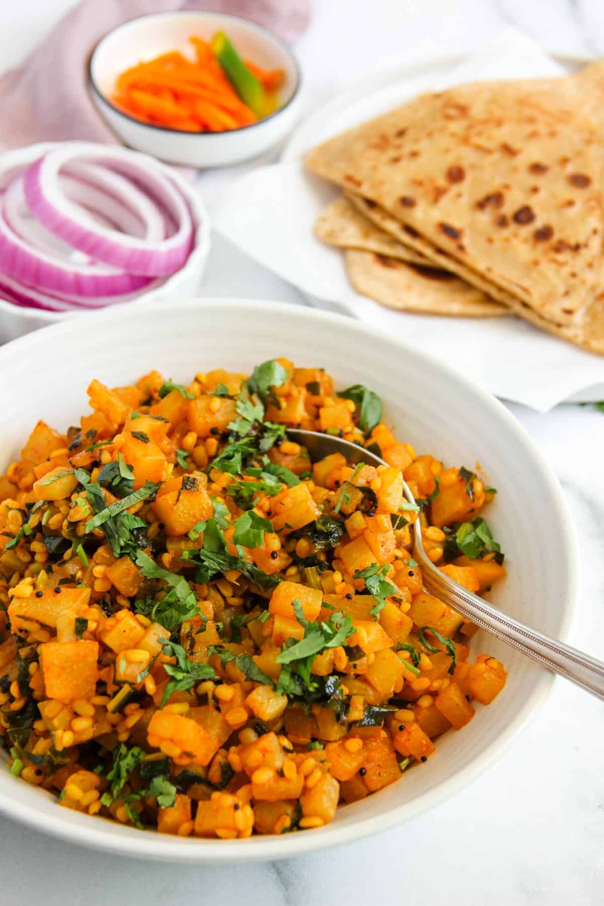 Kohlrabi curry served in a white bowl with parathas