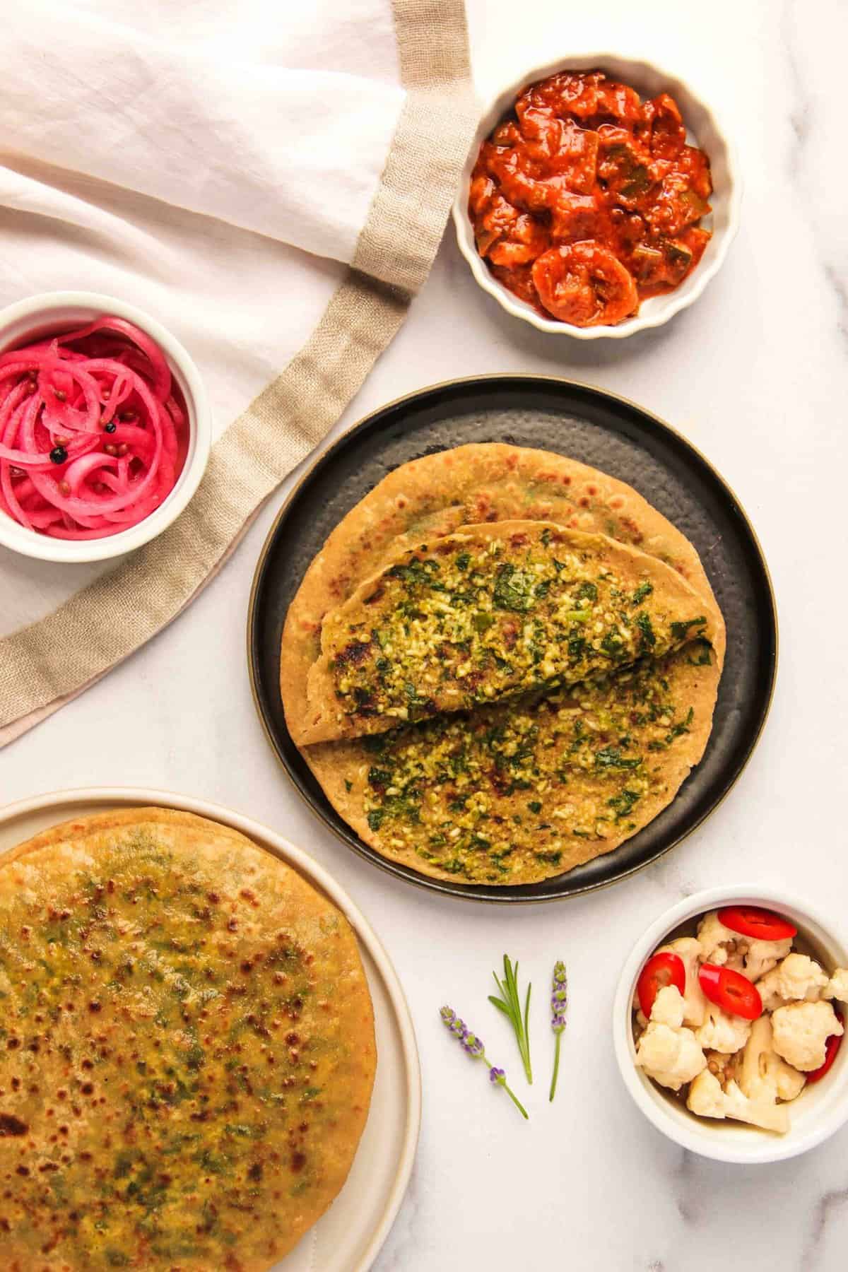 Palak Paneer paratha in a plate split open to show the inside filling