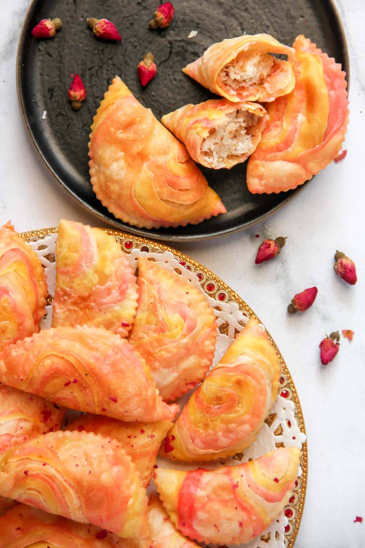 rose coconut karanji on a platter and in a black plate  
