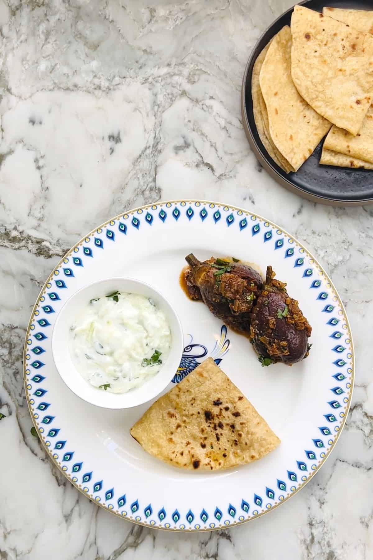 Vegan masala eggplant curry served with roti and raita 
