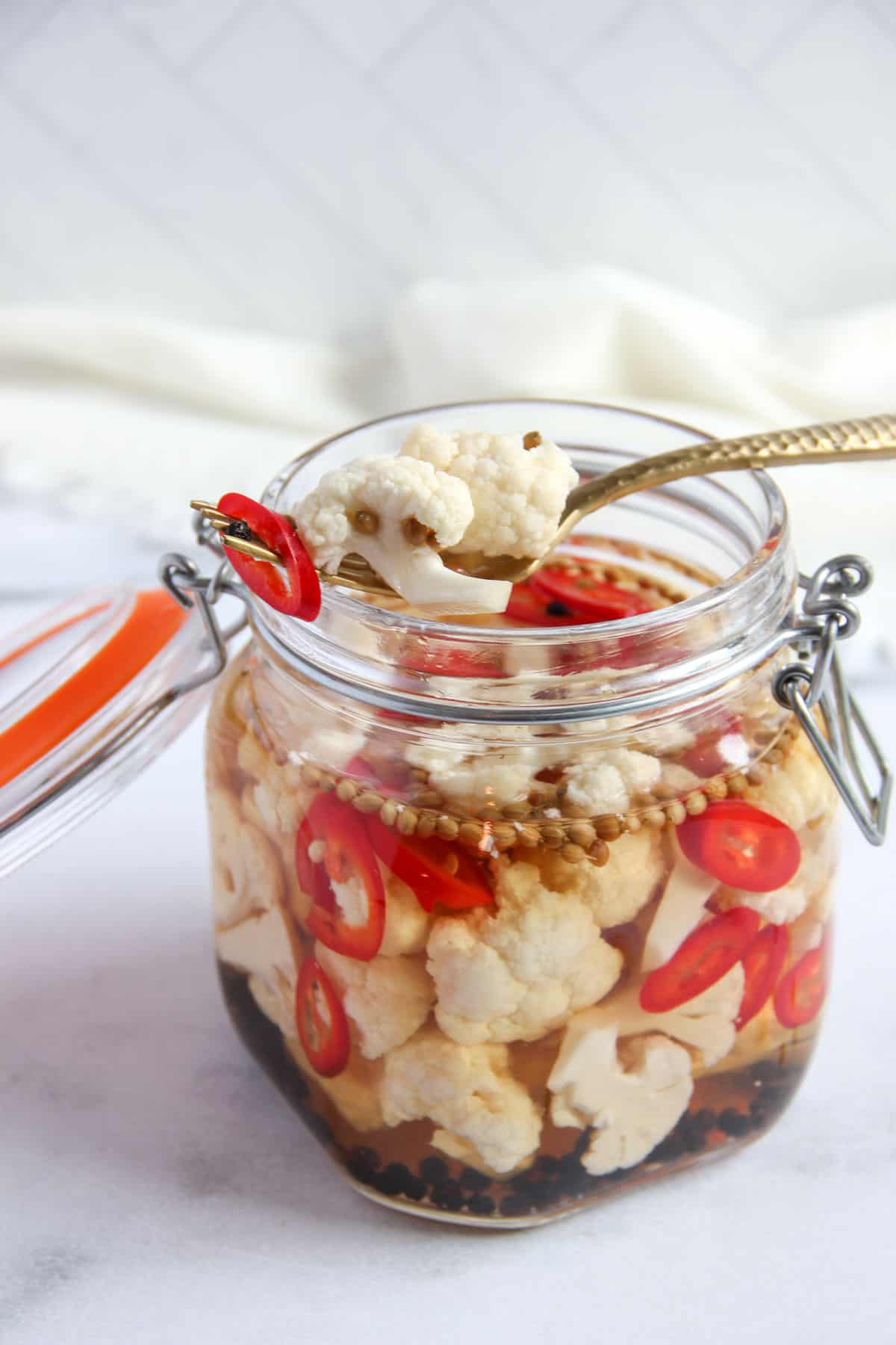 pickled cauliflower with red chilies and whole spices in a glass jar