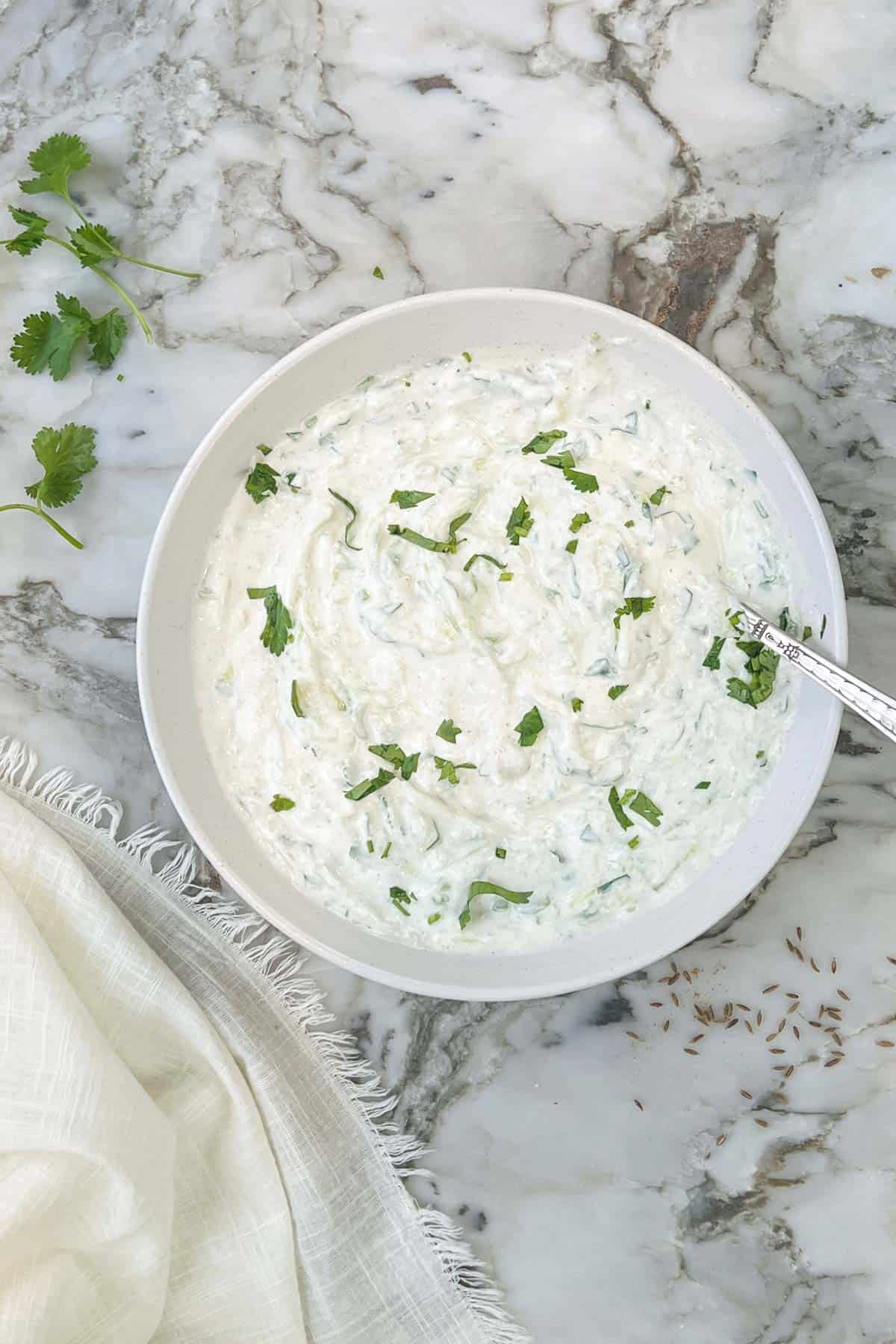 cooling cucumber raita garnished with cilantro 