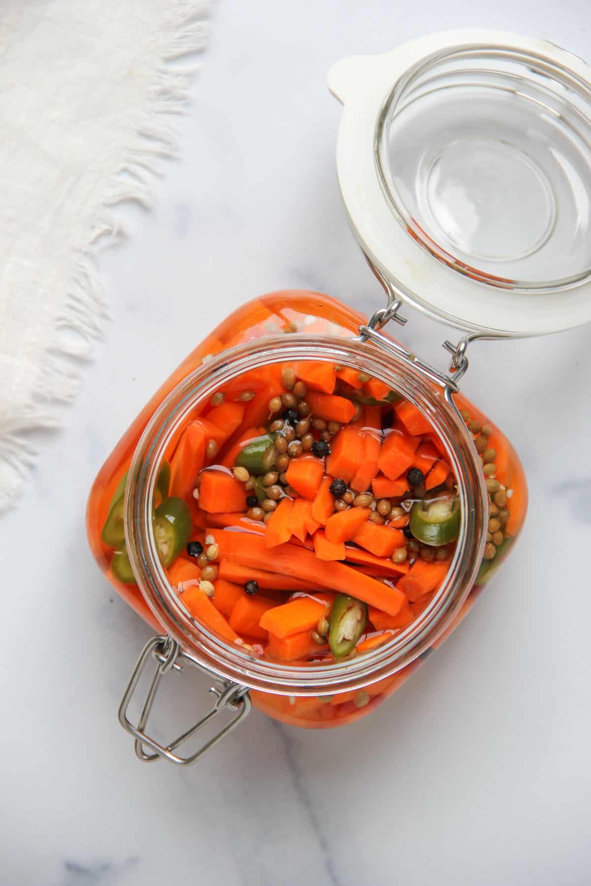 glass jar with pickled carrots and whole spices 