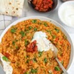 khichdi served in a white bowl with yogurt and pickles