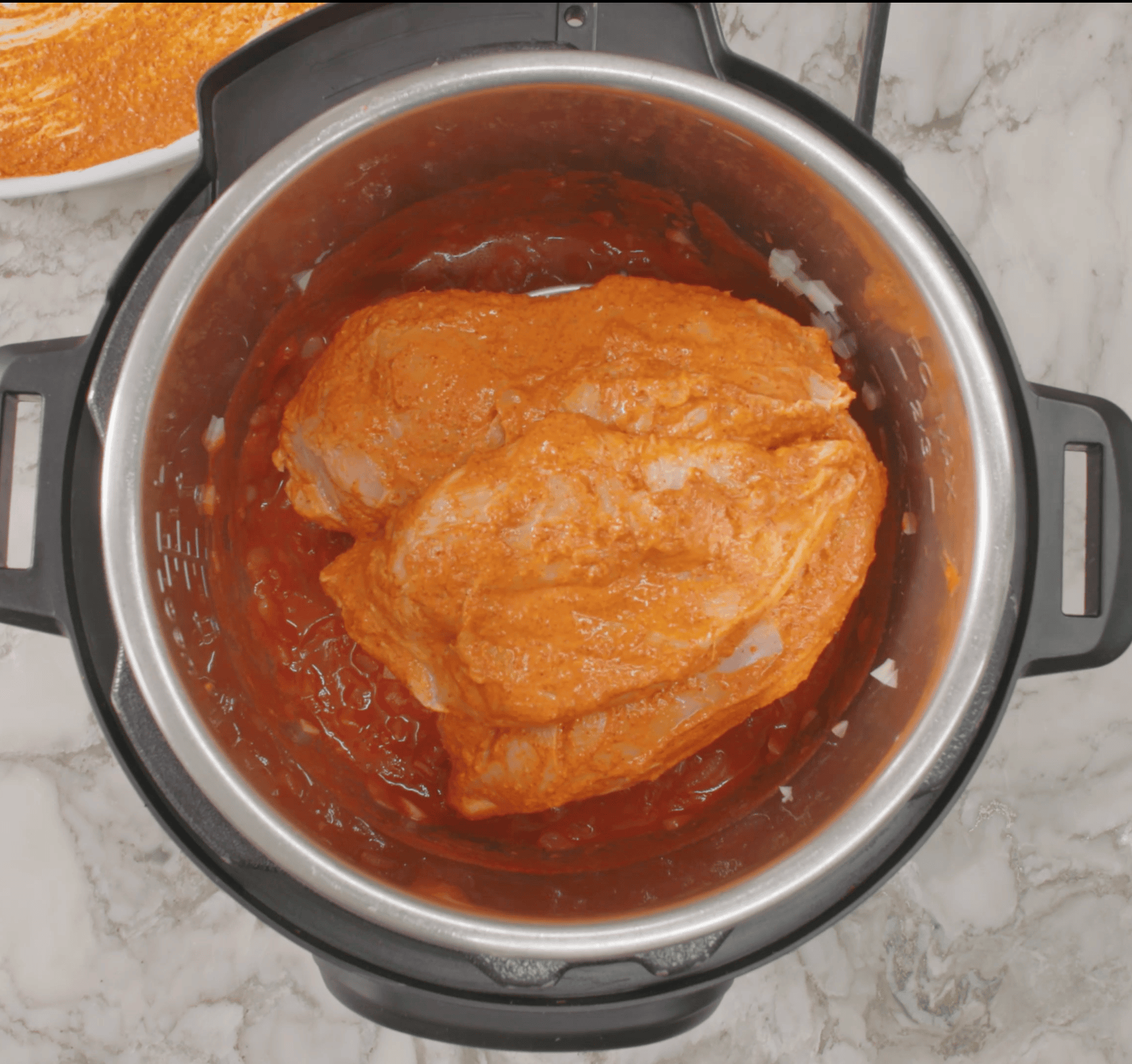 marinated chicken placed over the trivet in the Instant Pot