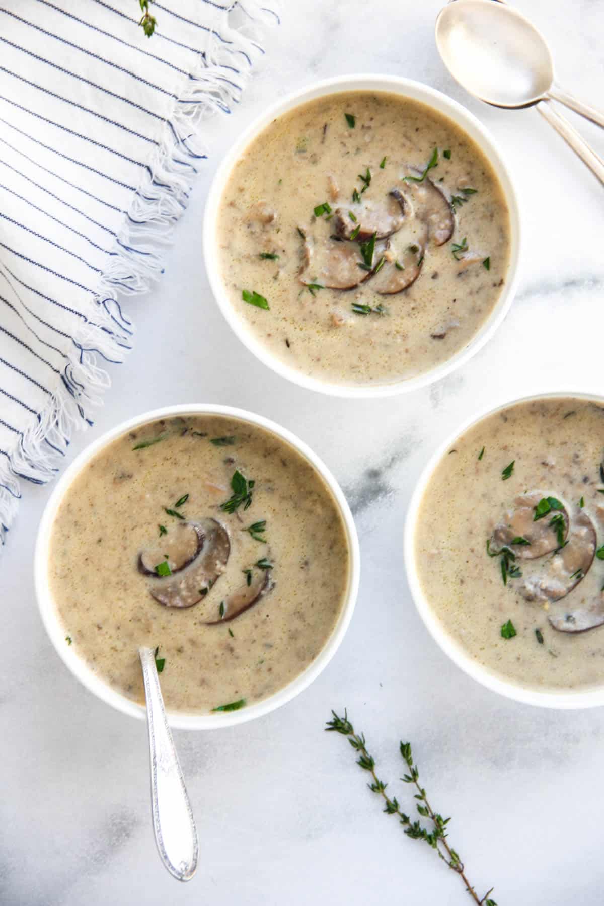 mushroom soup garnished with fresh thyme and served in white bowls 