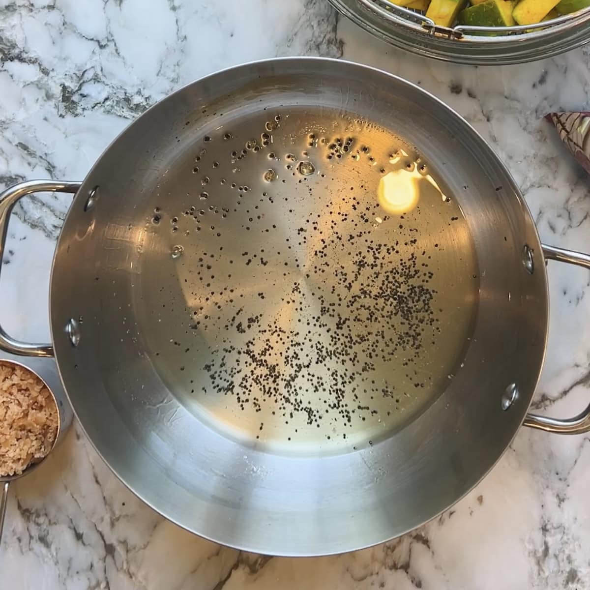 mustard seeds added to oil in a kadai