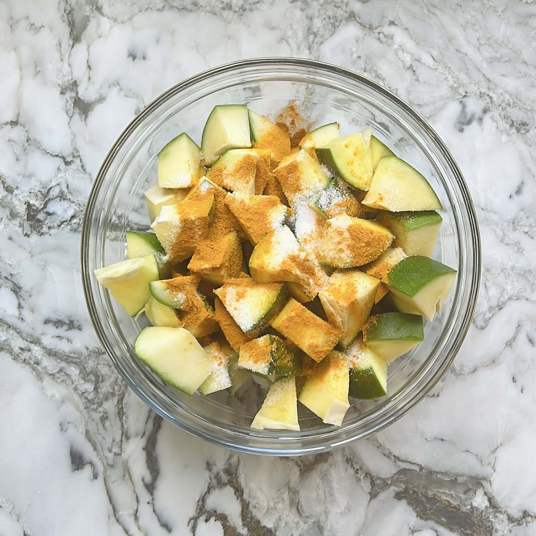 adding turmeric and salt to raw mango pieces 
