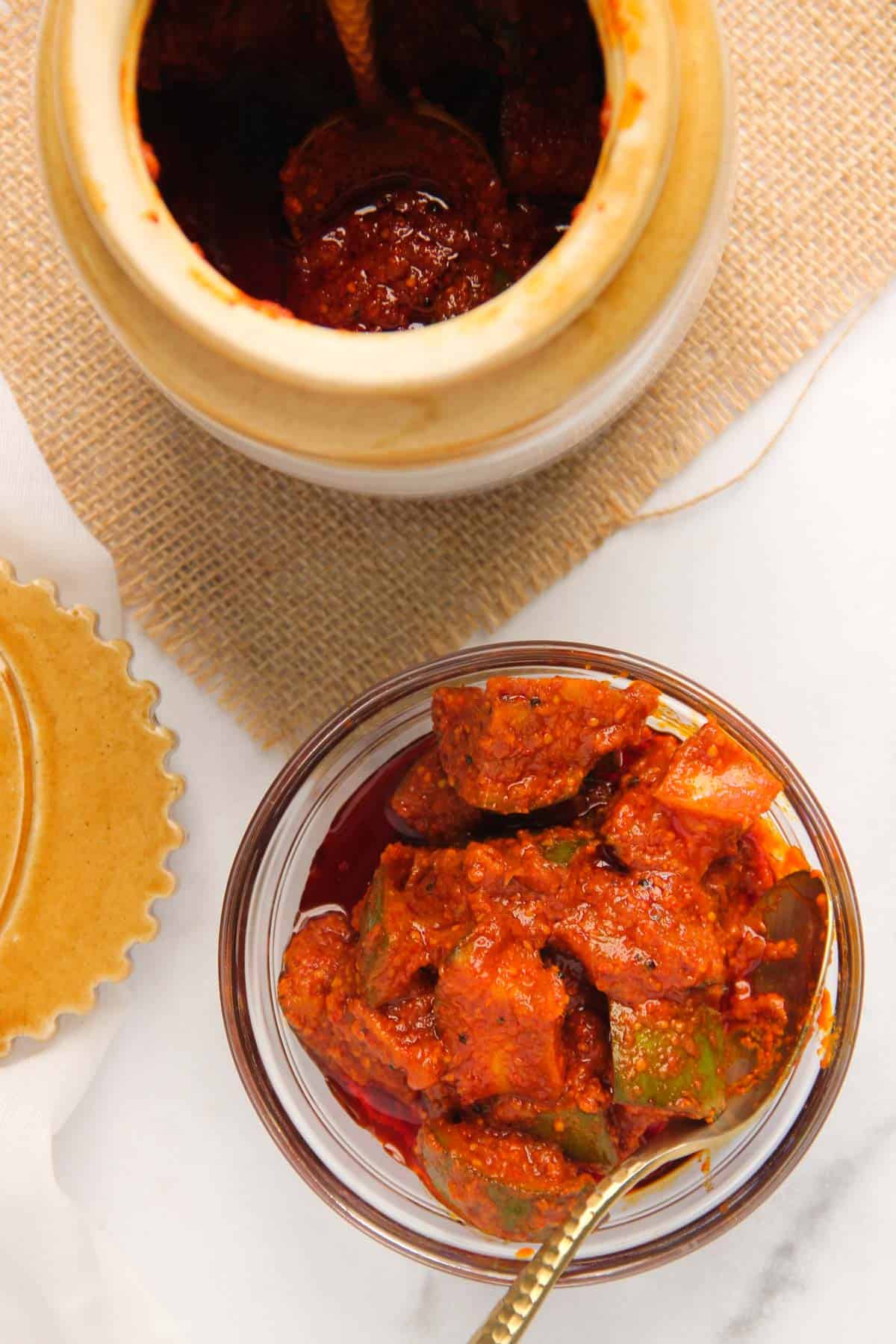 mango pickle in a glass serving bowl  and in a ceramic pickle jar