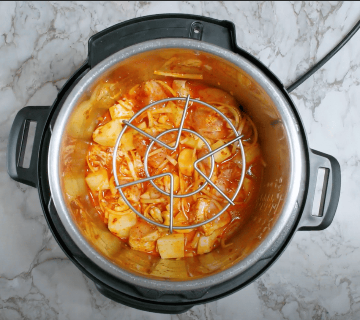 tall trivet placed over chicken massaman curry in the Instant Pot.