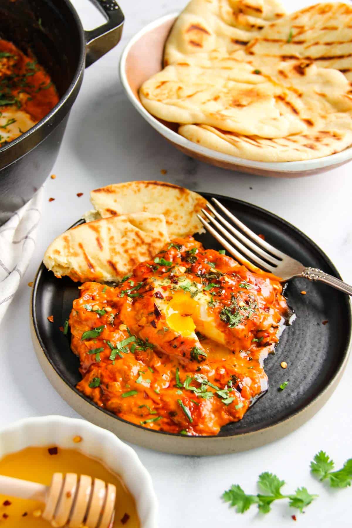 makhani shakshuka served in a black plate with bread