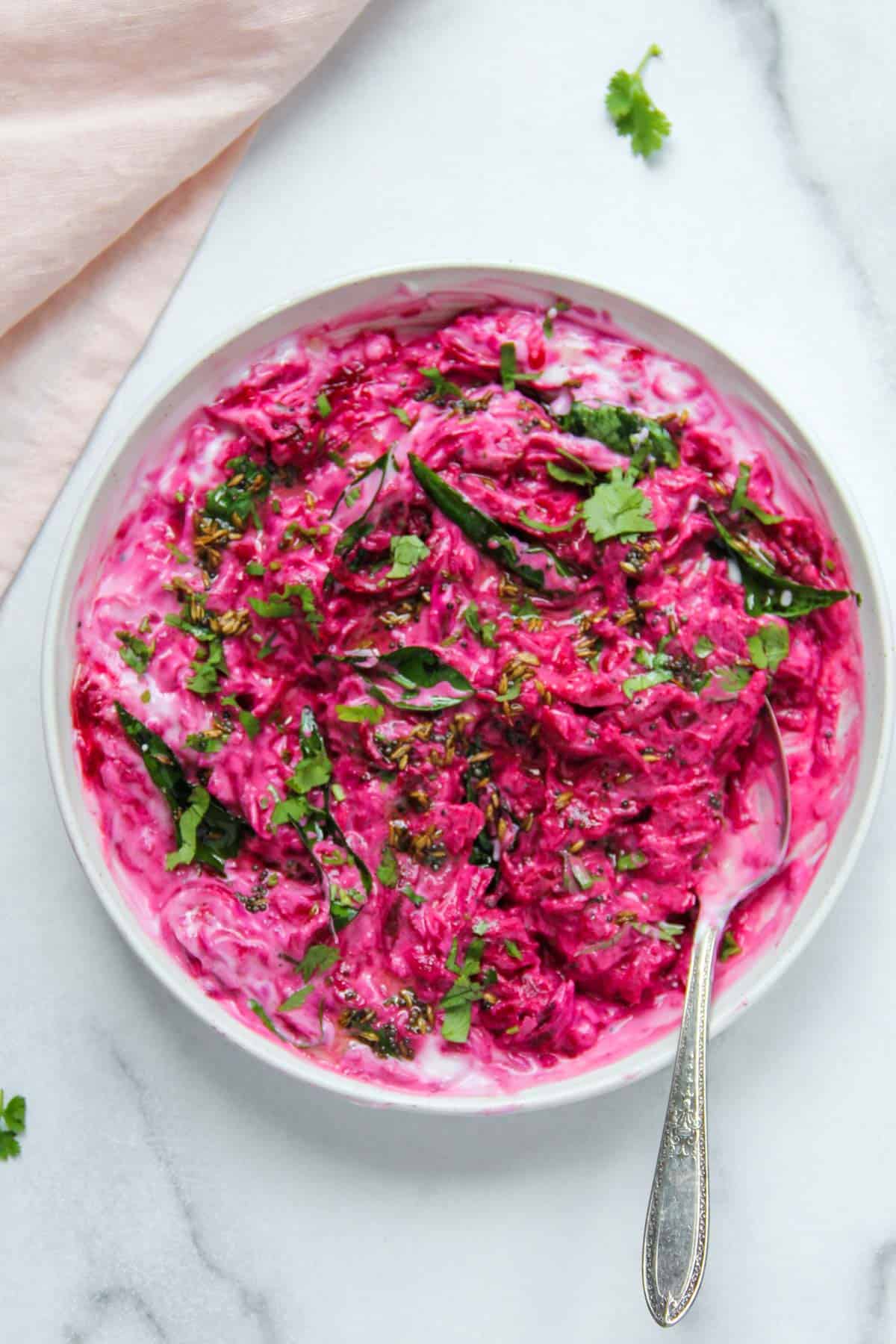 beet koshimbir in a white bowl garnished with cilantro and curry leaves