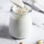 cashew cream dripping from a spoon into a glass bottle