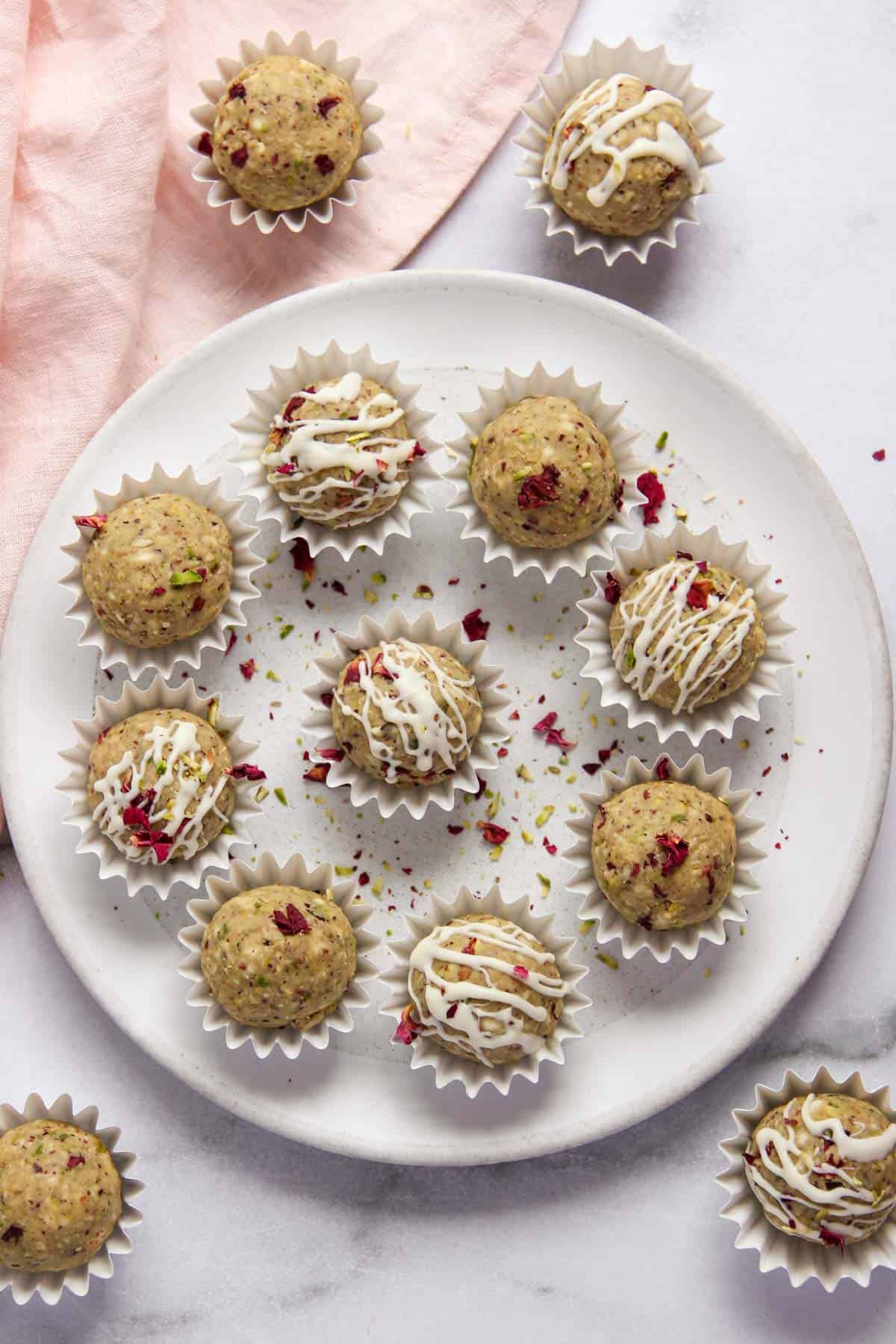 oats pistachio laddu in a white platter garnished with sliced pistachios and rose petals 