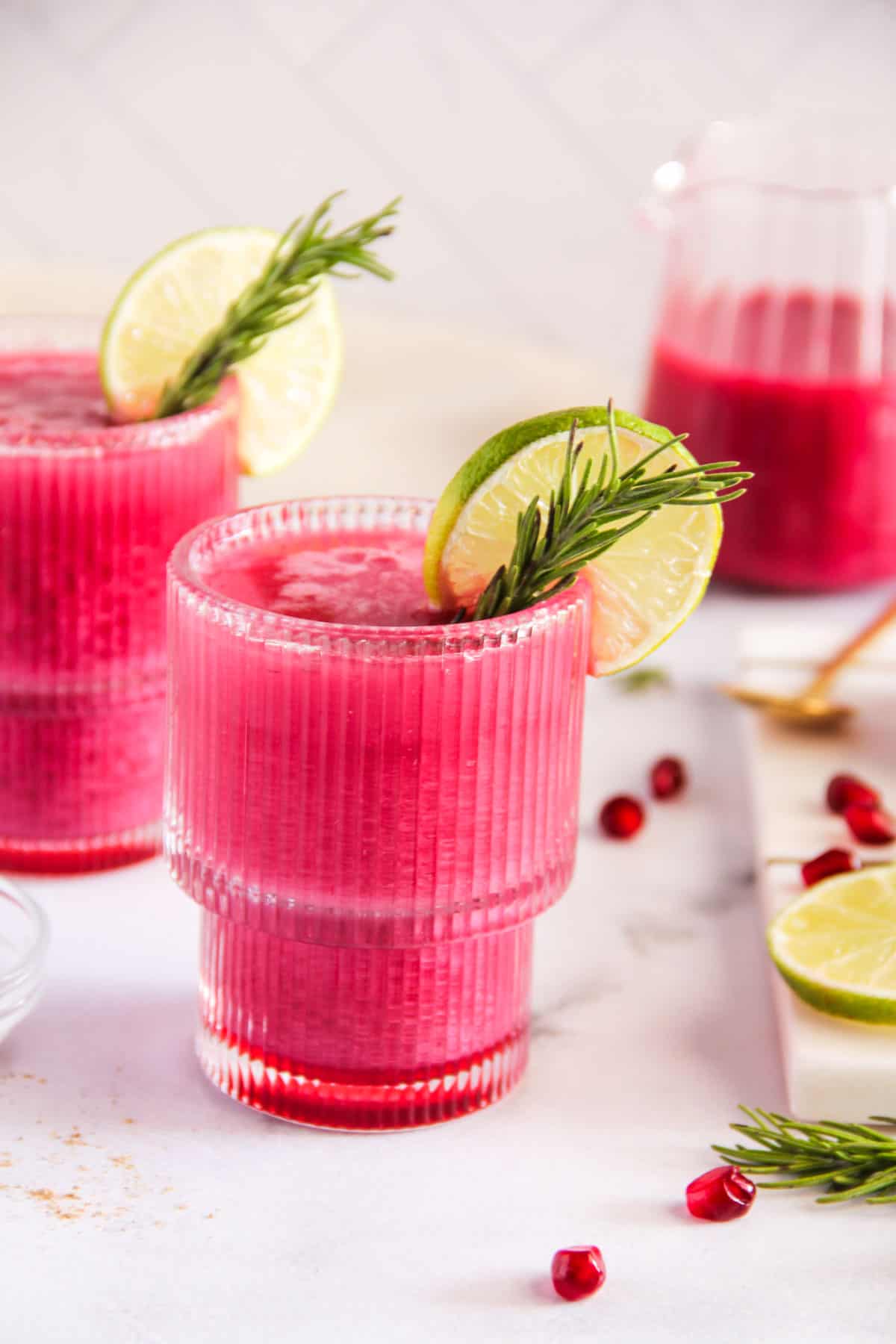 pomegranate spritz served in glasses with rosemary and lime garnish 